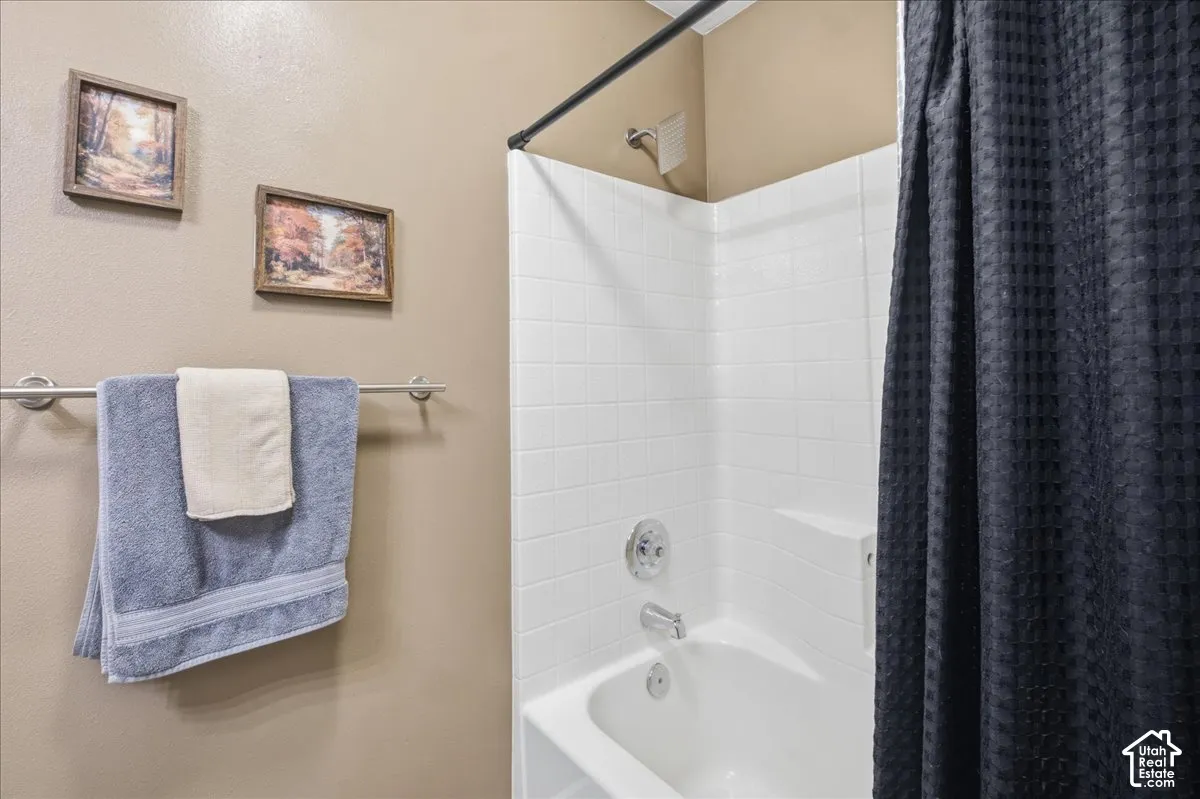 Bathtub and shower combination with white subway tile surround, integrated shower shelf, and chrome fixtures