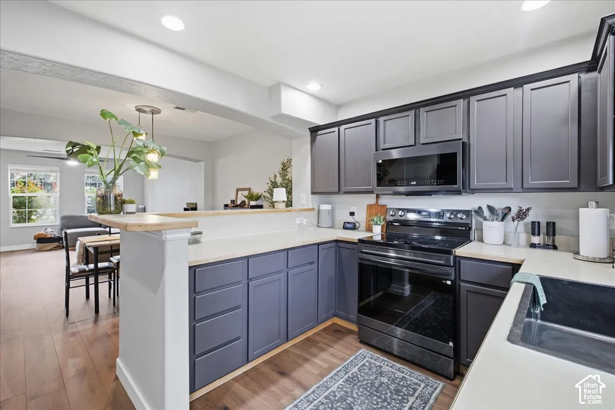 Kitchen featuring dark cabinetry, light countertops, built-in microwave, and electric range