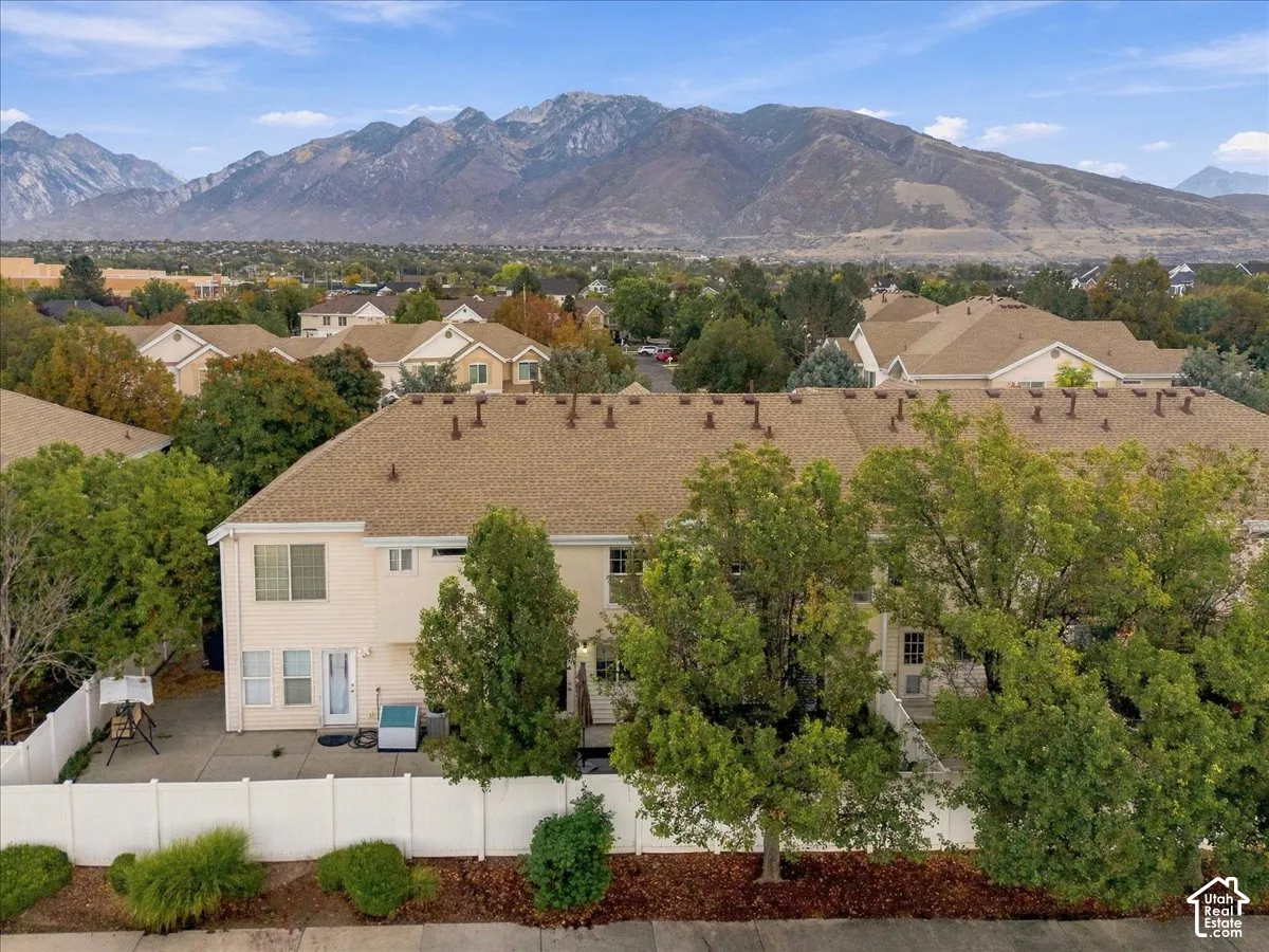 Rear exterior with a concrete patio, white privacy fencing, and mature trees