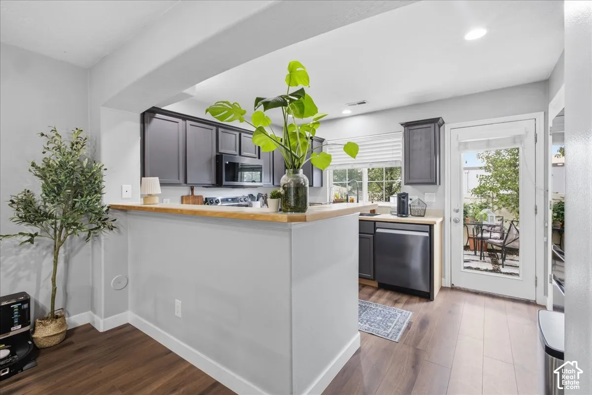 Kitchen featuring dark wood-finish cabinetry, light wood-finish countertops, and stainless steel appliances