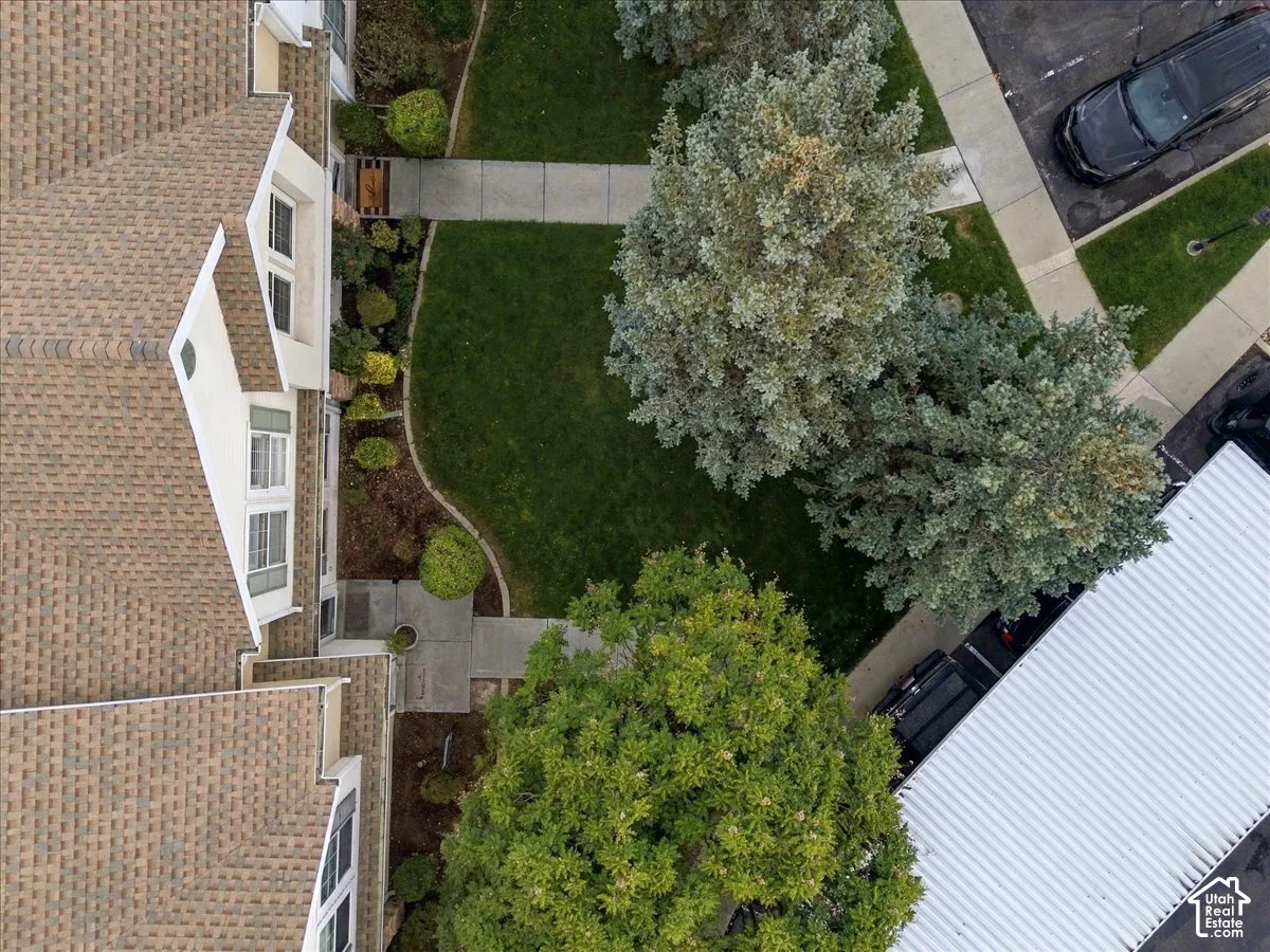 Pitched shingle roof, landscaped front yard with mature trees, concrete pathways, and an attached carport