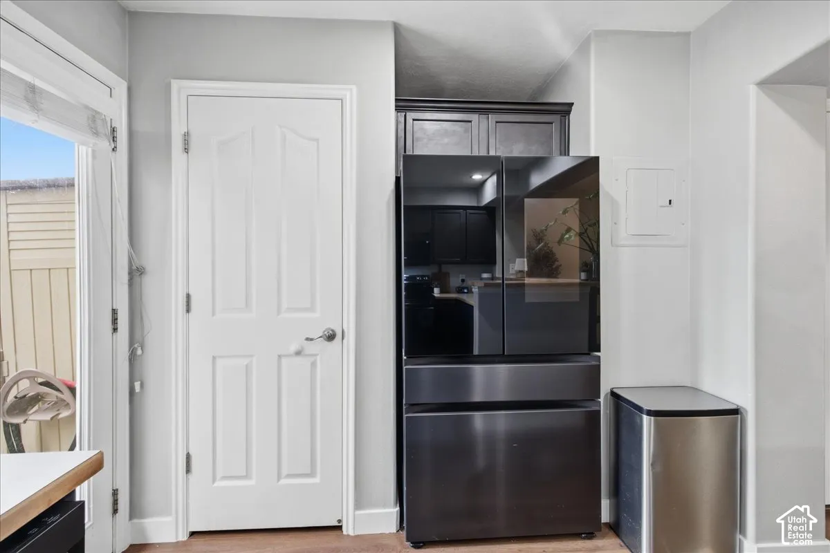 White paneled door with brushed nickel hardware, built-in dark cabinetry, and black stainless steel refrigerator