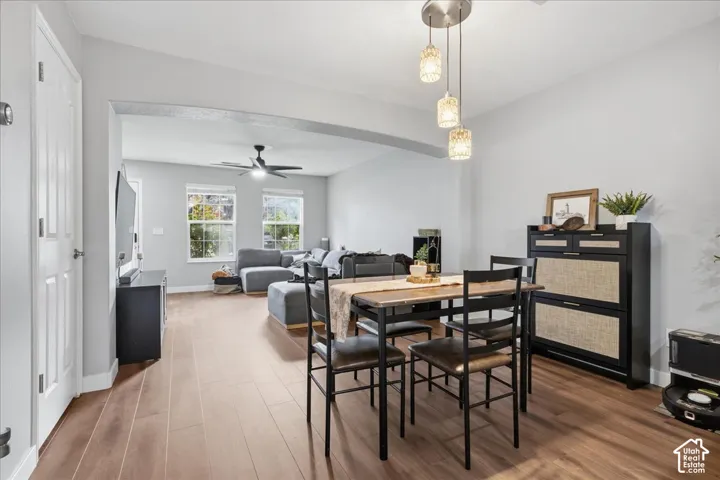Wood-finish flooring throughout, with a dining area featuring a modern pendant light fixture and an arched entryway to the living space