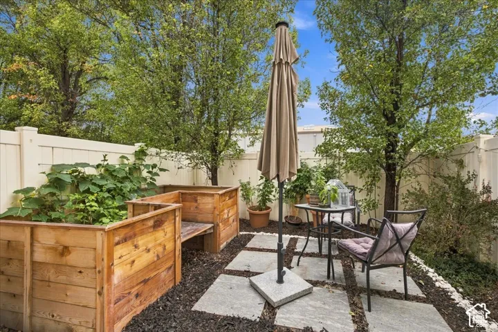 Private outdoor space featuring a stone paver patio, wood-finish raised garden beds, and mature trees
