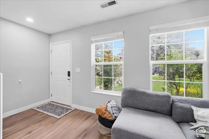 Light gray wall paint, wood-finish flooring, white trim, recessed lighting, and a white entry door with smart lock