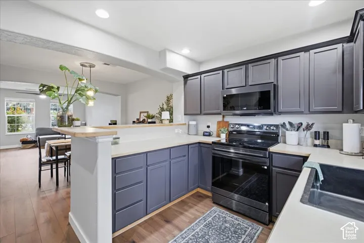 Kitchen featuring dark cabinetry, light countertops, built-in microwave, and electric range