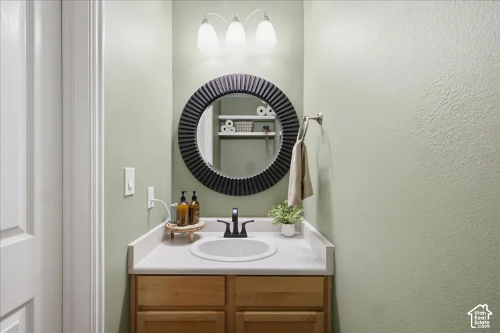 Vanity featuring wood-finish cabinetry, a single basin sink, and a white countertop
