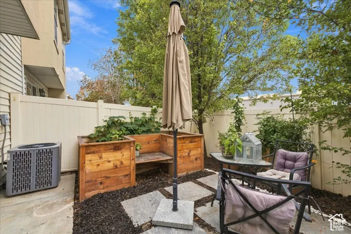 Private patio featuring a built-in wooden planter bench, paver stone hardscaping, and a privacy fence