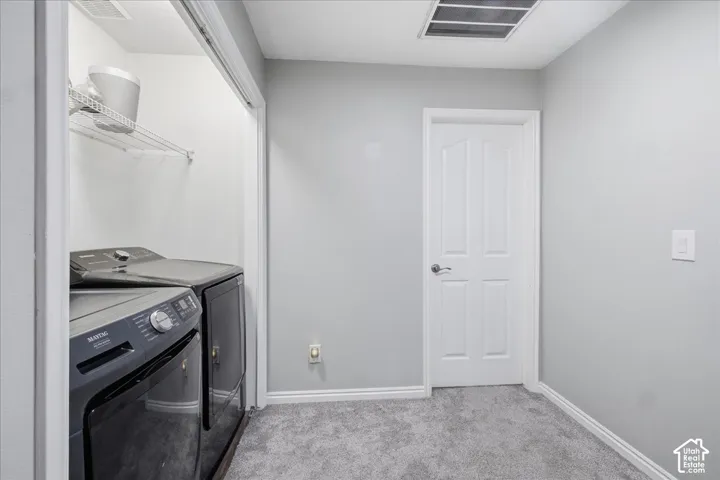 Dedicated laundry area with built-in shelving, durable gray carpeting, and a white paneled door