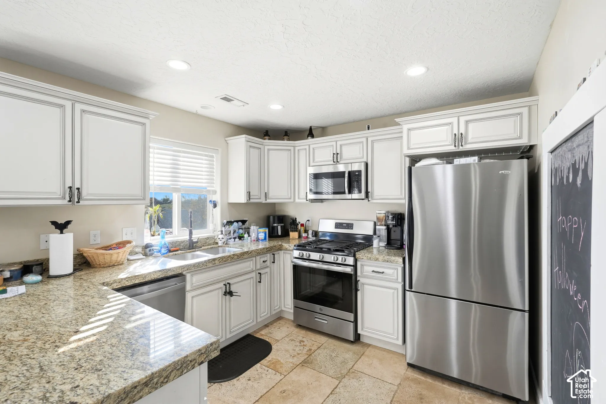 Kitchen featuring white cabinetry, light-toned countertops, stainless steel appliances, recessed lighting, and tile flooring