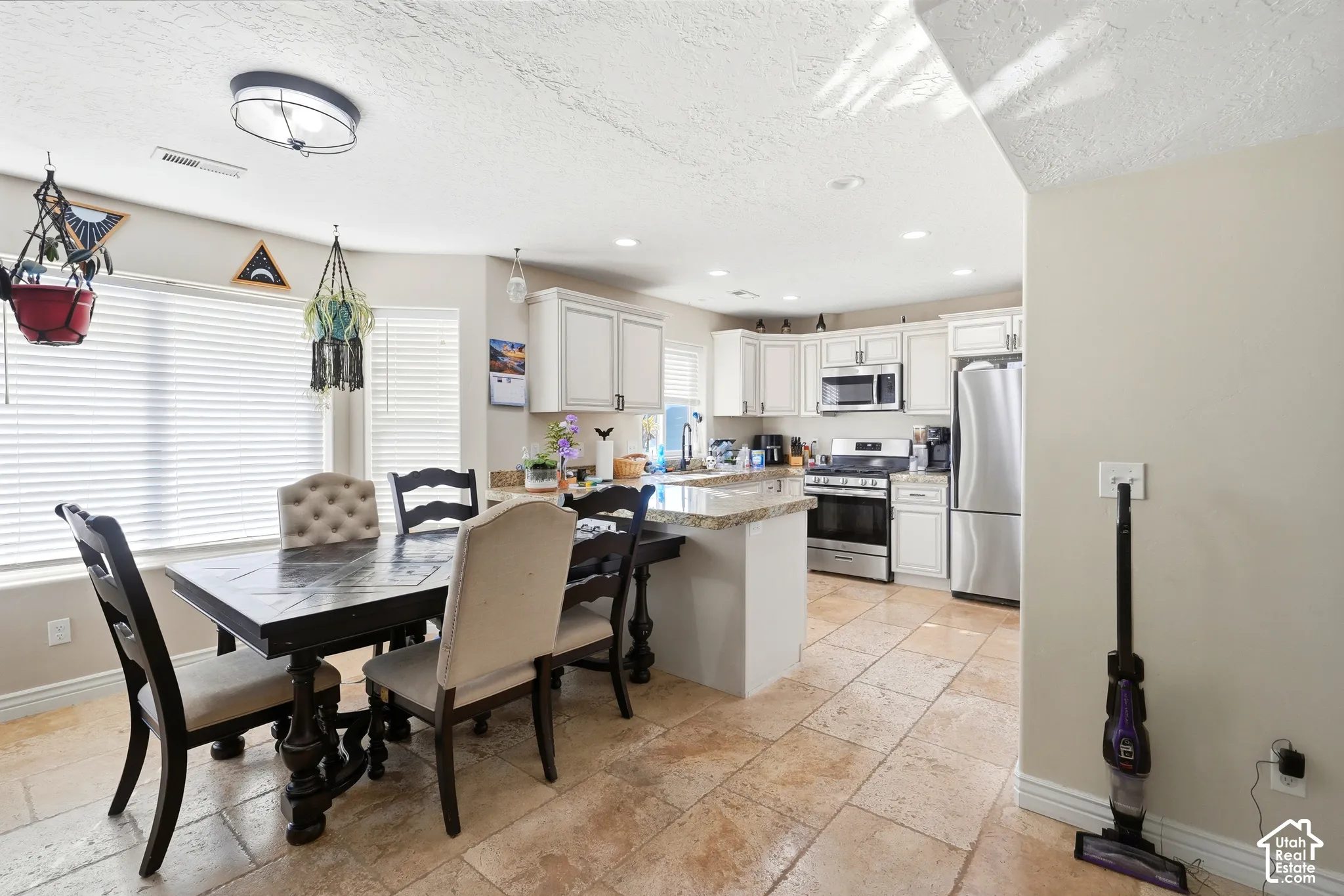 Kitchen featuring white cabinetry, stainless steel appliances, and a central island with a light-toned countertop