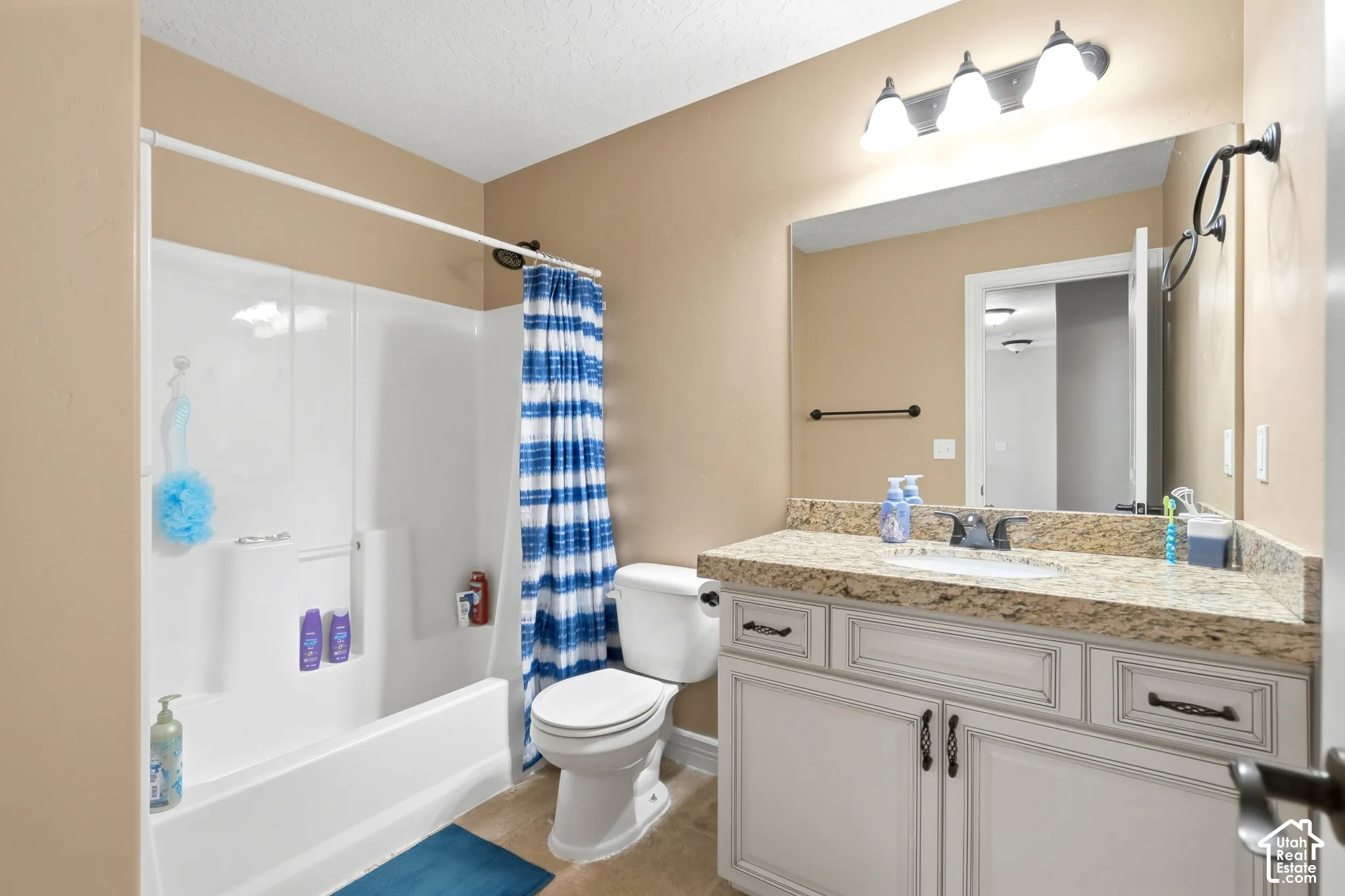 Bathroom featuring a white tub/shower combination, a vanity with a light-colored countertop, and a built-in sink