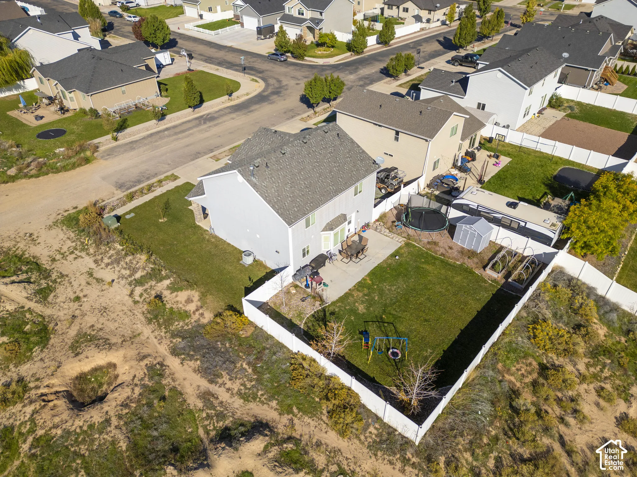 Backyard featuring a white vinyl fence, manicured lawn, and concrete patio