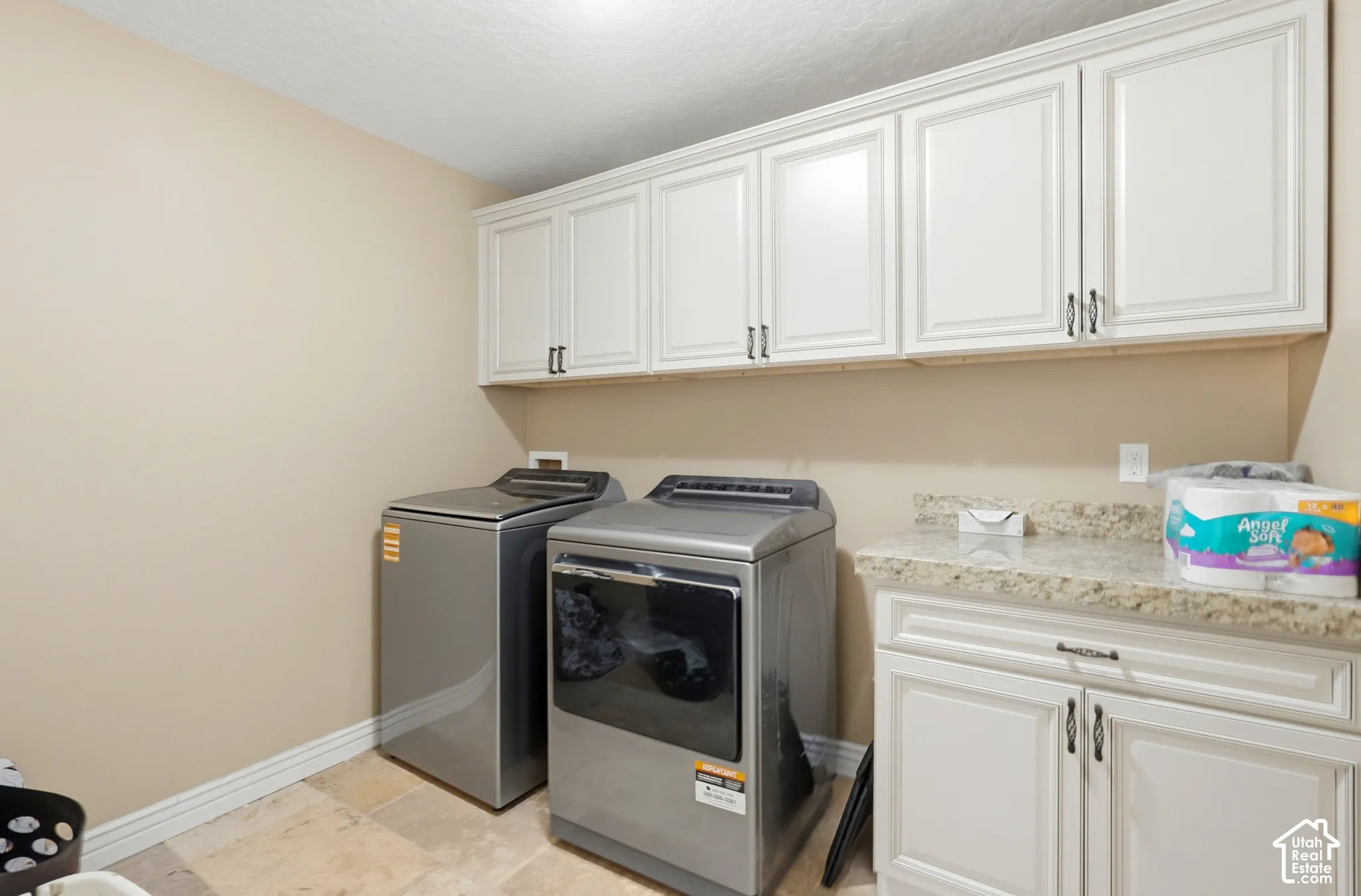 Upper and lower white cabinetry, light-toned walls, tiled flooring, and a speckled countertop
