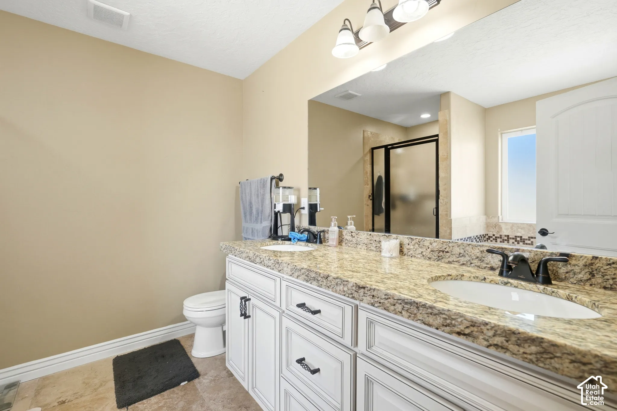 Dual vanity with stone countertop, white cabinetry, and matte black fixtures