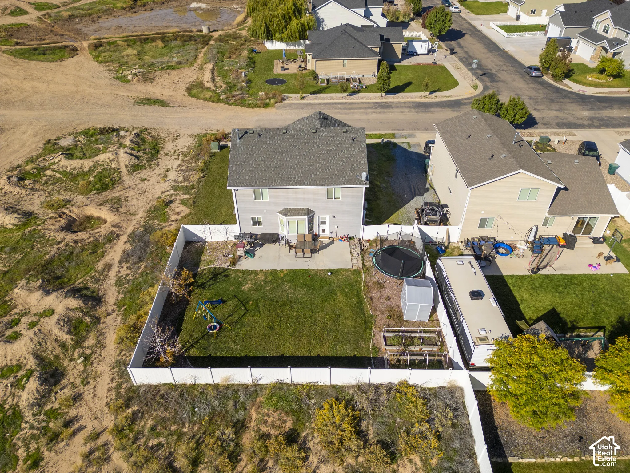 Two-story residence with a gray shingle roof, a bay window, and a rear patio