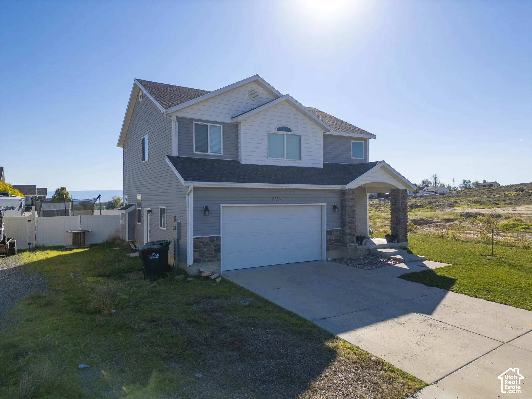 Two-story residence featuring siding and stone accents, an attached garage, and a covered entry