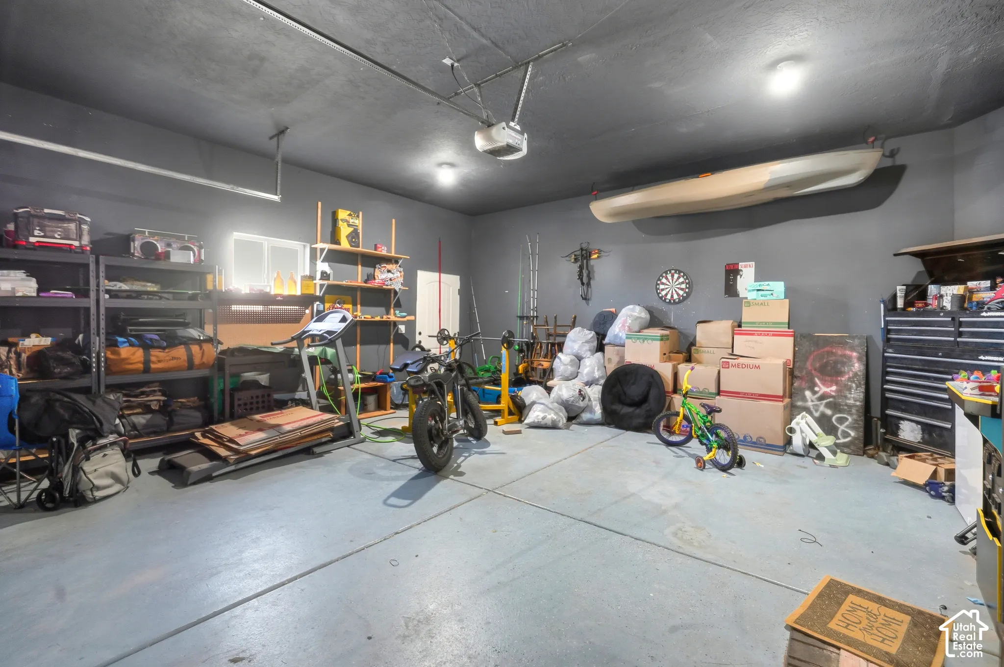 Spacious garage with painted concrete flooring, overhead lighting, and an automatic garage door opener