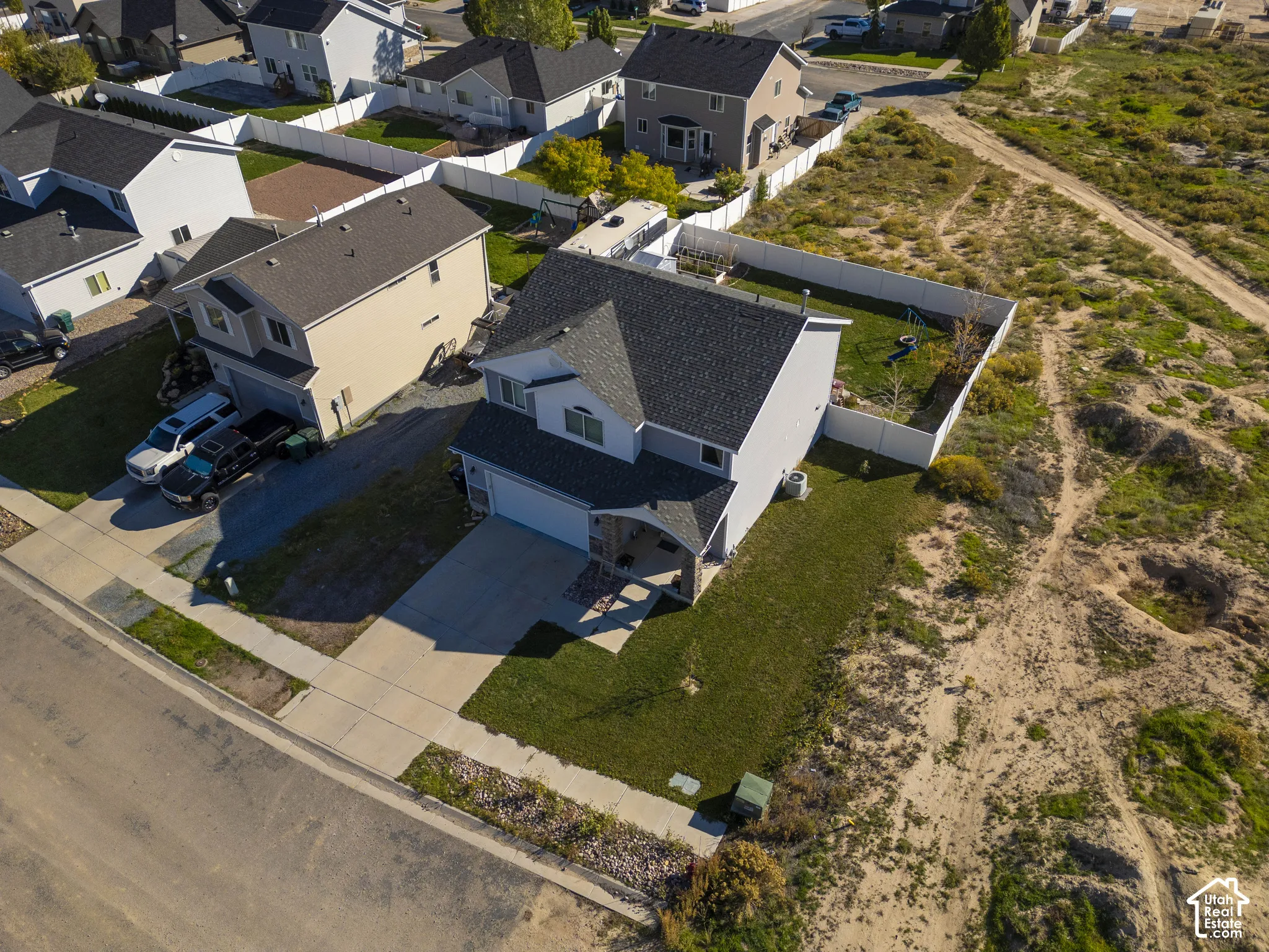 Two-story residence with an attached two-car garage, mature landscaping, and a fenced backyard