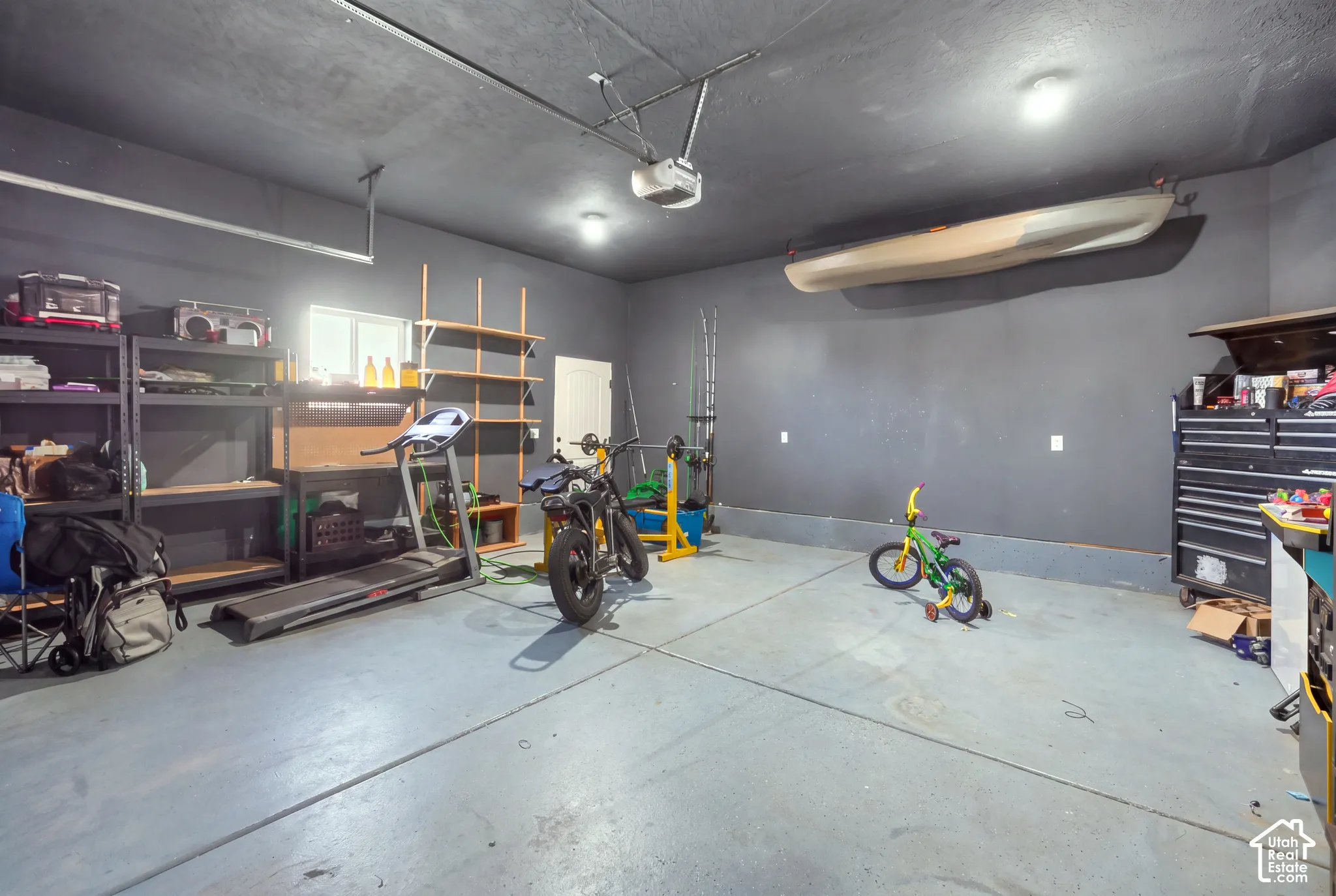 Finished garage with concrete flooring, built-in shelving, and overhead lighting