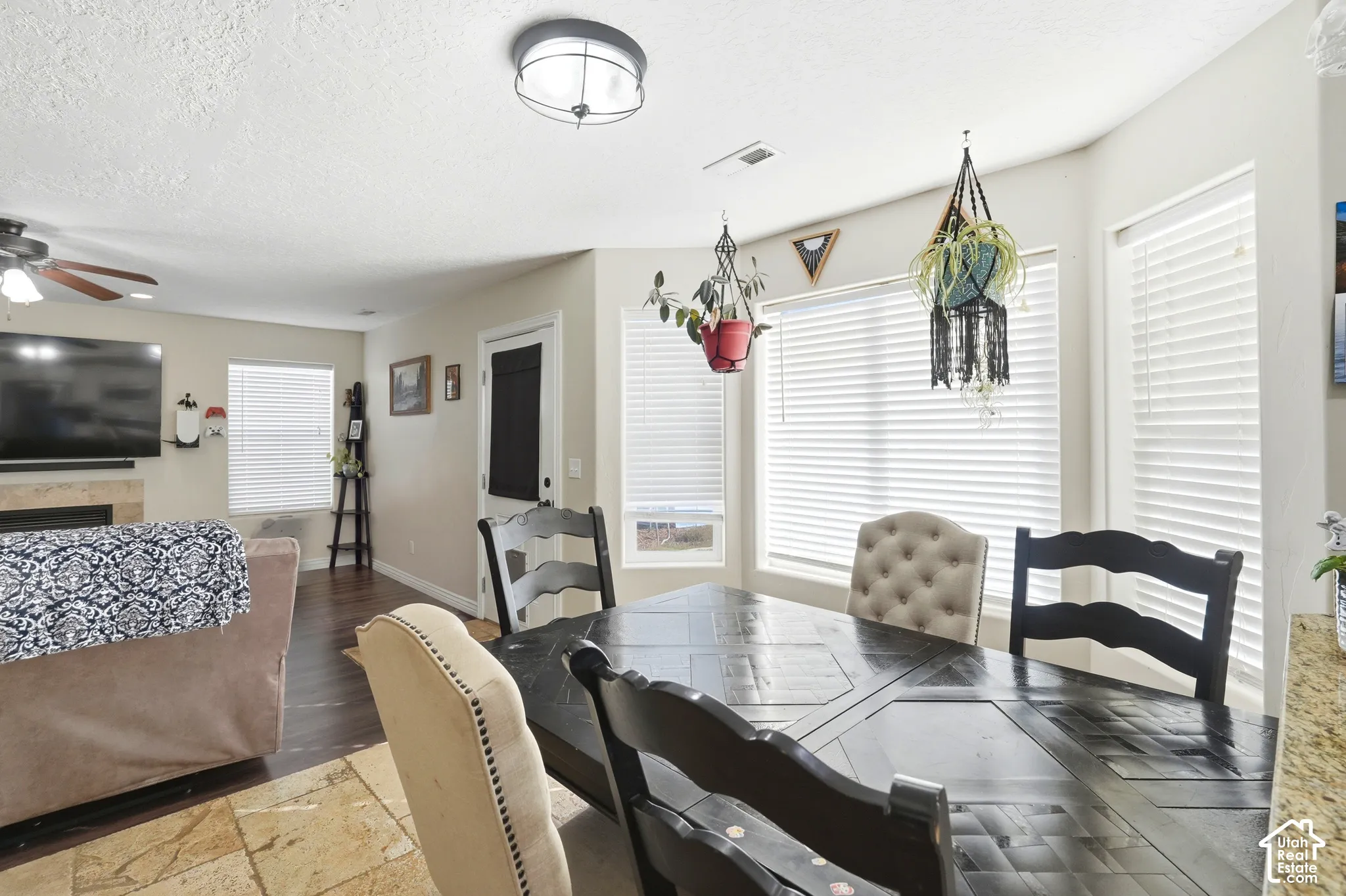 Recessed lighting, wood-finish flooring, fireplace with stone surround, ceiling fan, and large windows with blinds