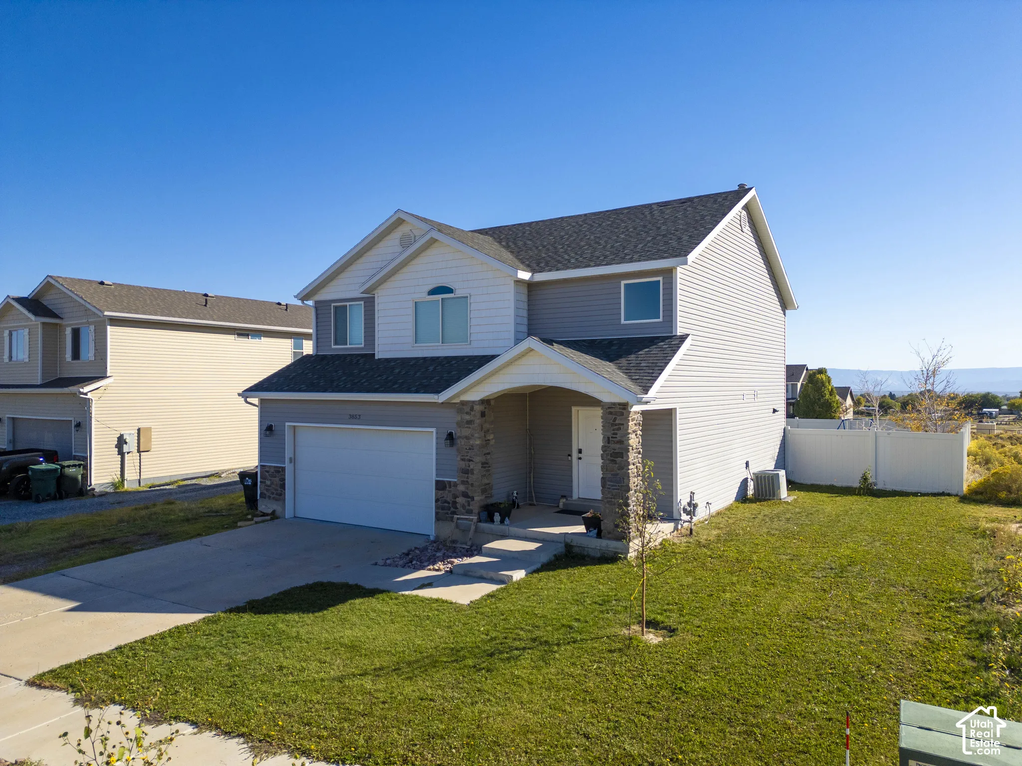 Two-story residence featuring light gray siding with white trim accents and dark gray shingle roofing