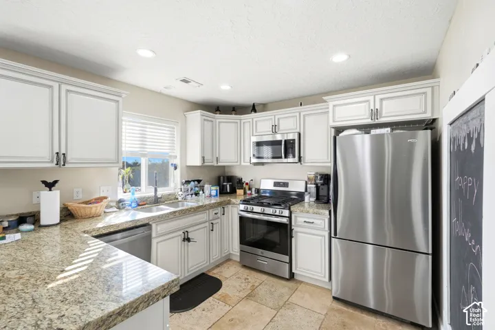 Kitchen featuring white cabinetry, light-toned countertops, stainless steel appliances, recessed lighting, and tile flooring
