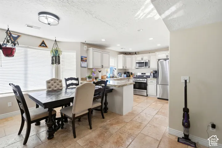 Kitchen featuring white cabinetry, stainless steel appliances, and a central island with a light-toned countertop