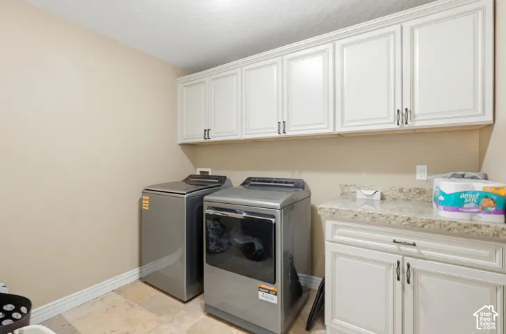 Upper and lower white cabinetry, light-toned walls, tiled flooring, and a speckled countertop