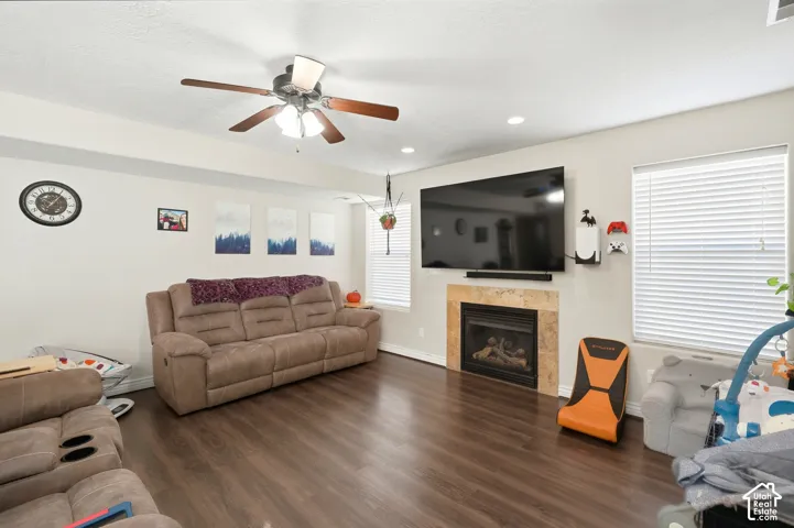 Wood-finish flooring, recessed lighting, ceiling fan, fireplace with stone surround, and window with blinds