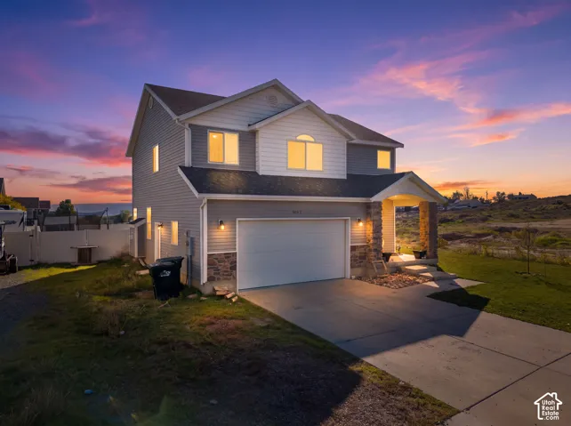 Two-story residence with a covered front porch featuring stone-clad pillars, an attached garage, and a concrete driveway