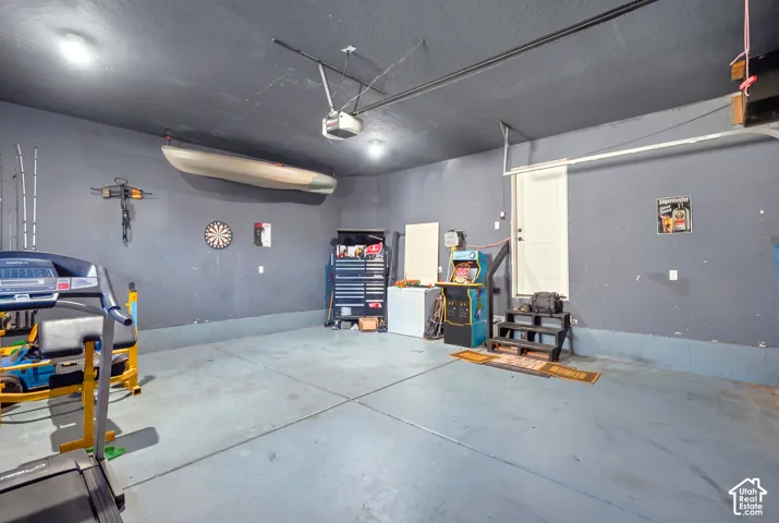 Spacious garage area featuring a concrete floor, painted walls, and overhead lighting