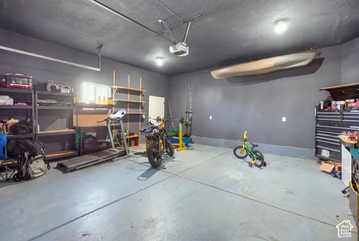 Finished garage with concrete flooring, built-in shelving, and overhead lighting