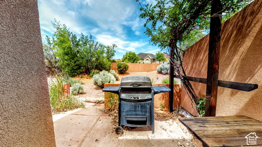 Paved patio area with stucco walls, wood fencing, and natural landscaping