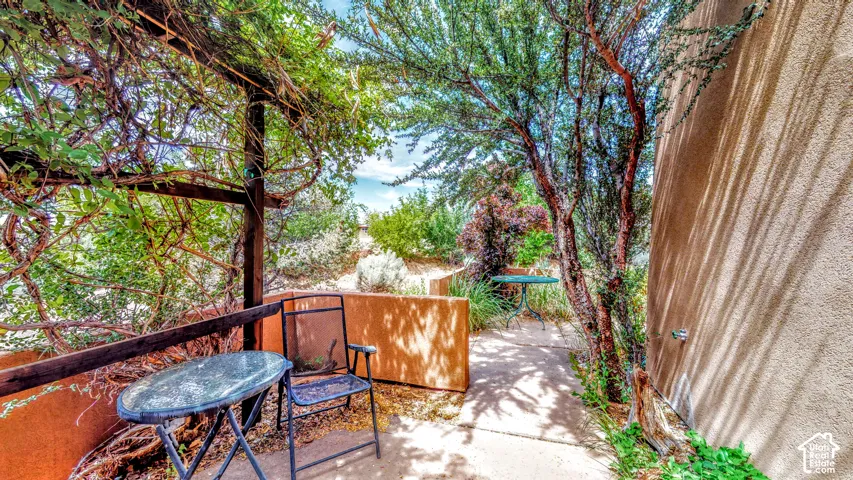 Outdoor patio with a wooden pergola structure and mature landscaping