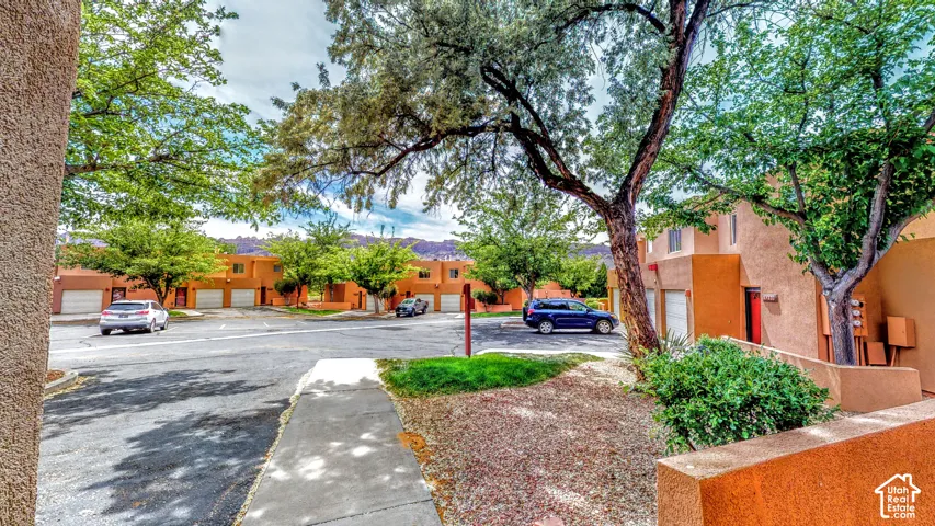 Multi-unit property with stucco exterior, attached garages, and mature trees
