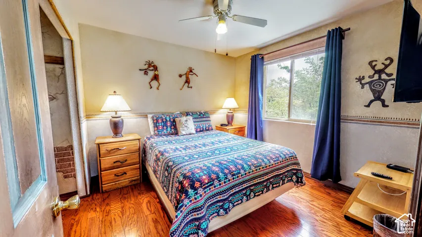 Wood-finish flooring, ceiling fan, and window with exterior scenery