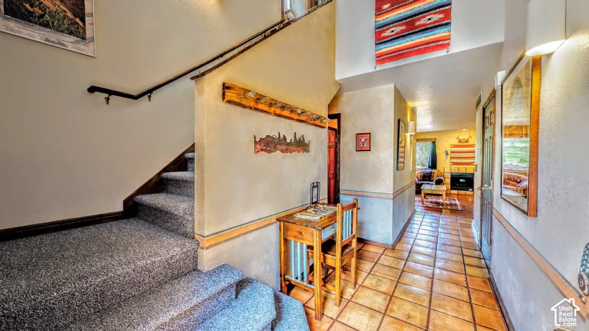 Tiled entryway flooring with wood trim accents and textured wall finishes