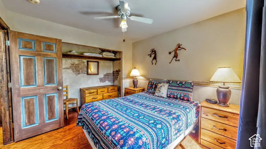 Wood-finish flooring throughout, ceiling fan with integrated lighting, and a built-in open closet with shelving