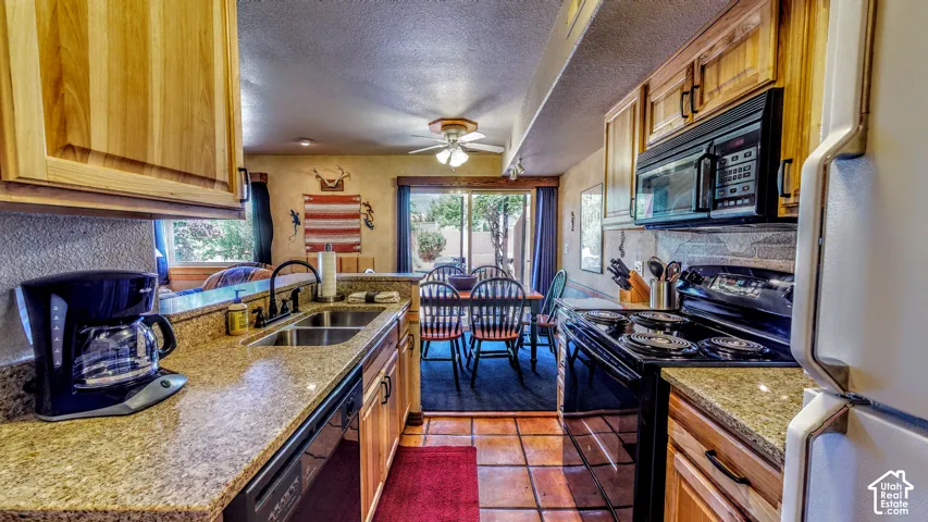 Kitchen featuring natural wood cabinetry, granite-finish countertops, and a double basin sink with a matte black faucet