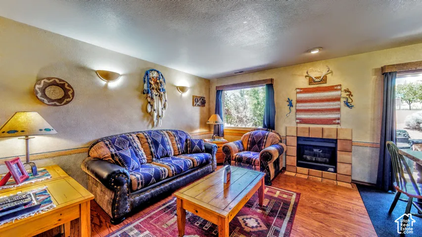 Built-in fireplace with tile surround, recessed lighting, wood-finish flooring, and multiple wall sconces