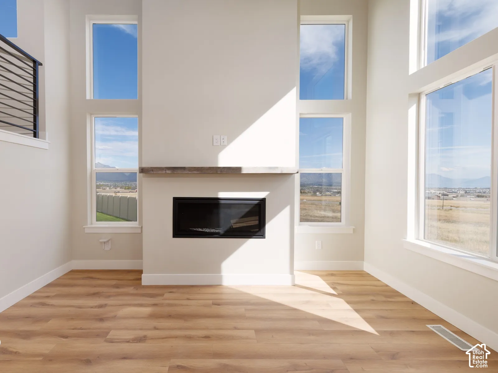 Hardwood-style flooring, a built-in fireplace with a wood-finish mantle, and multiple tall windows