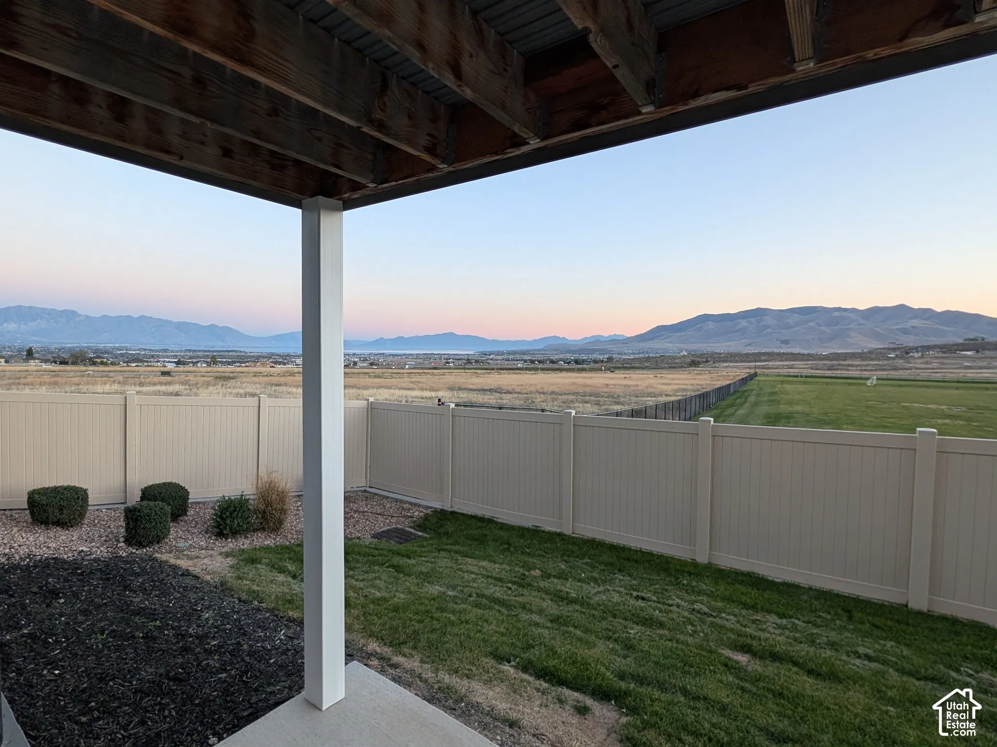 Covered patio with concrete flooring, framed by a white post