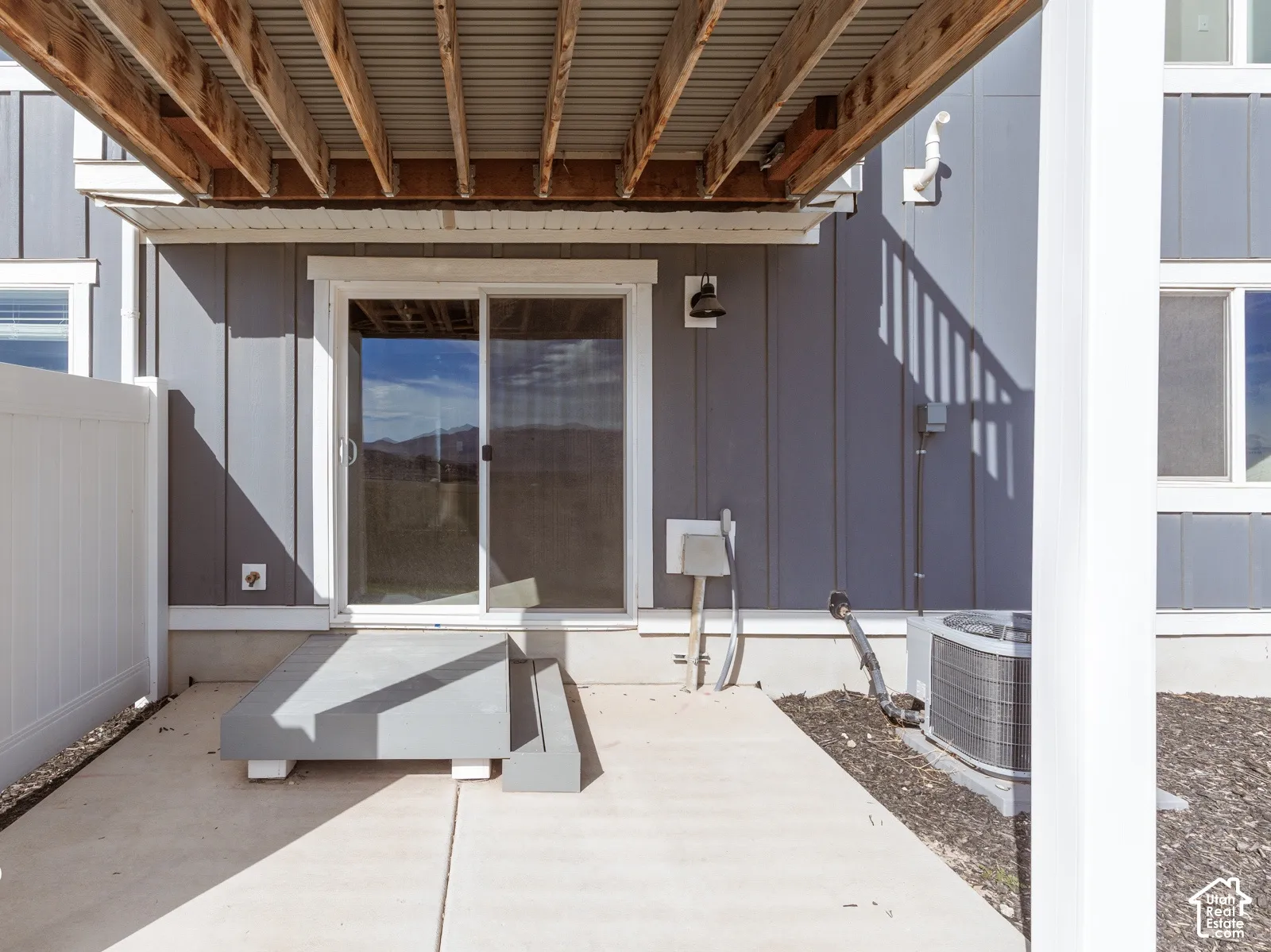 Concise concrete patio with privacy fence and sliding glass door access