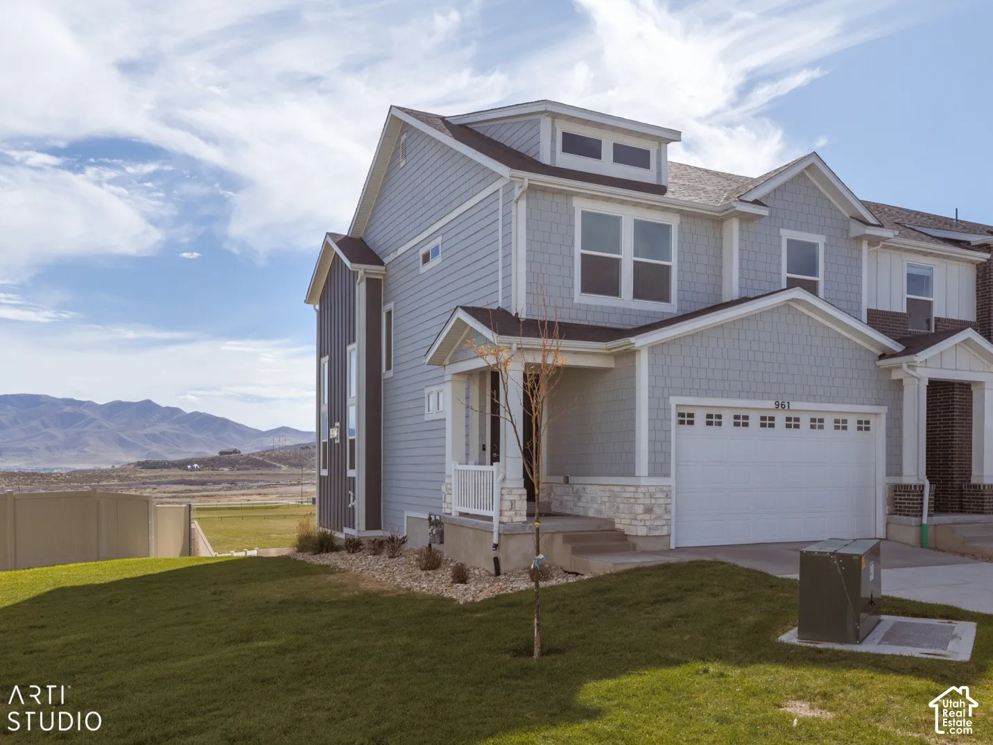 Two-story residence featuring light gray siding with shingle accents and white stone detailing