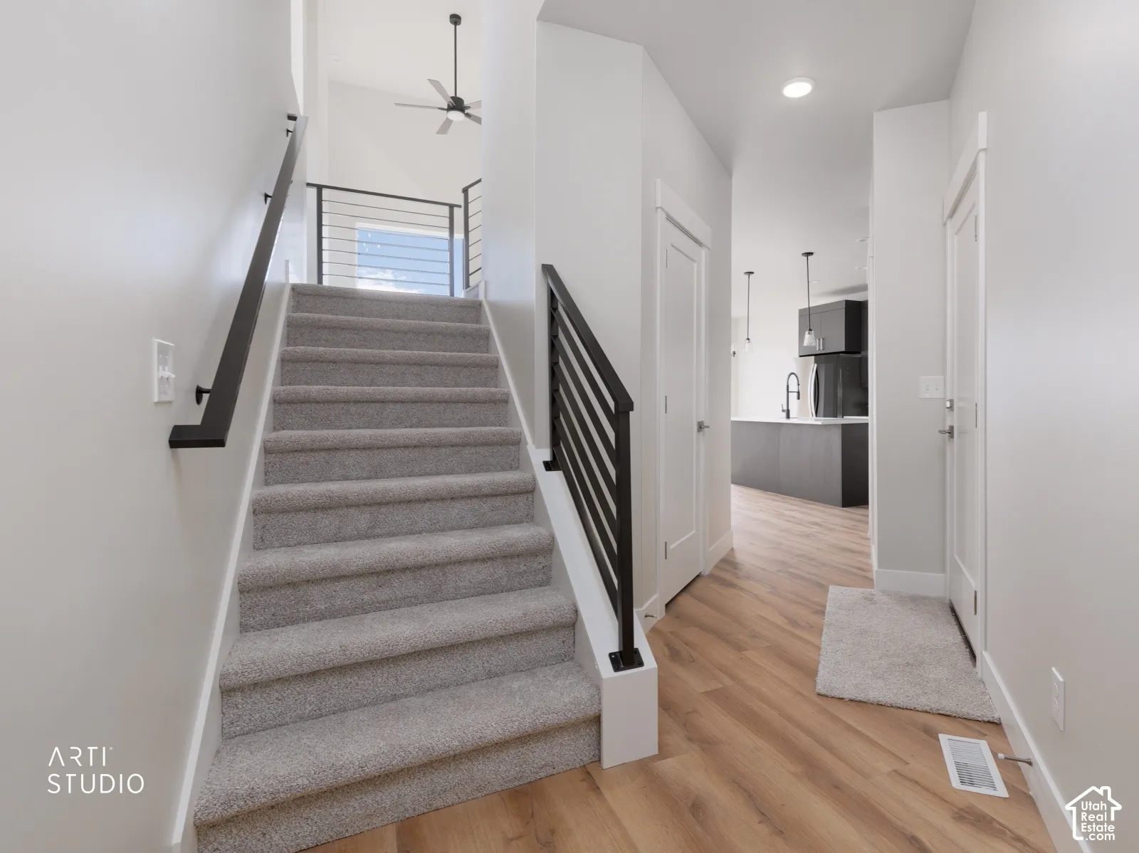 Hardwood-finish flooring, carpeted staircase, open-concept railing with horizontal balusters, recessed lighting, and a modern ceiling fan