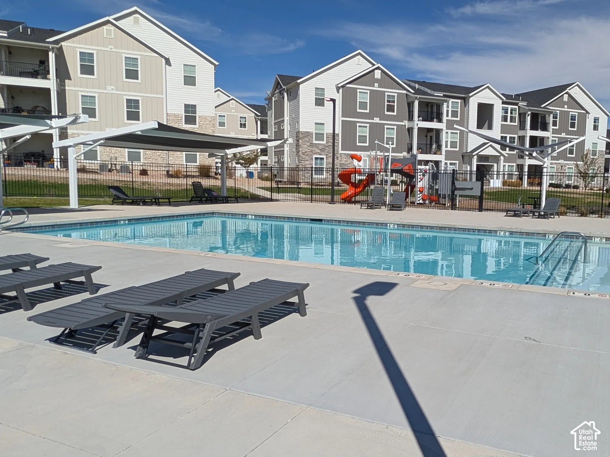 Outdoor swimming pool with integrated shallow area, surrounded by a paved deck