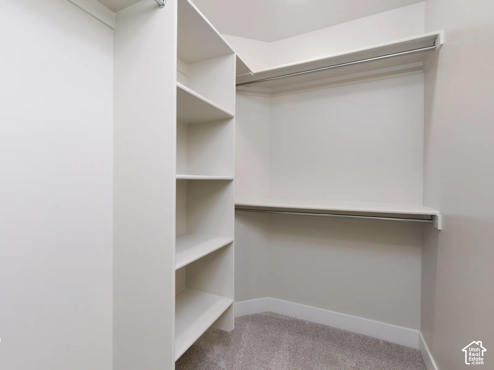 Custom closet system with built-in shelving, dual hanging rods, and light gray carpeting