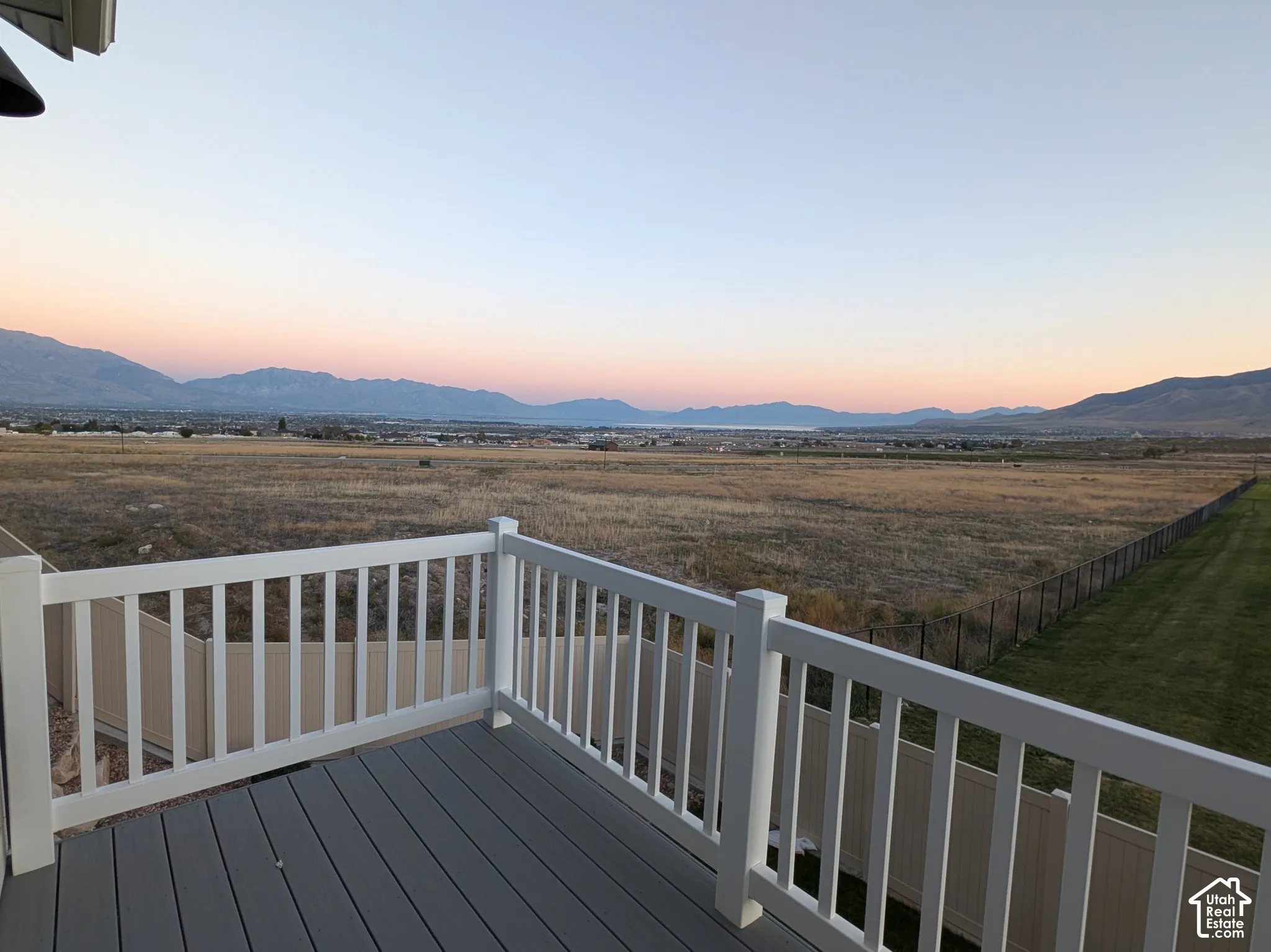 Second-story balcony with composite decking and white railing, overlooking a vast landscape with distant mountains