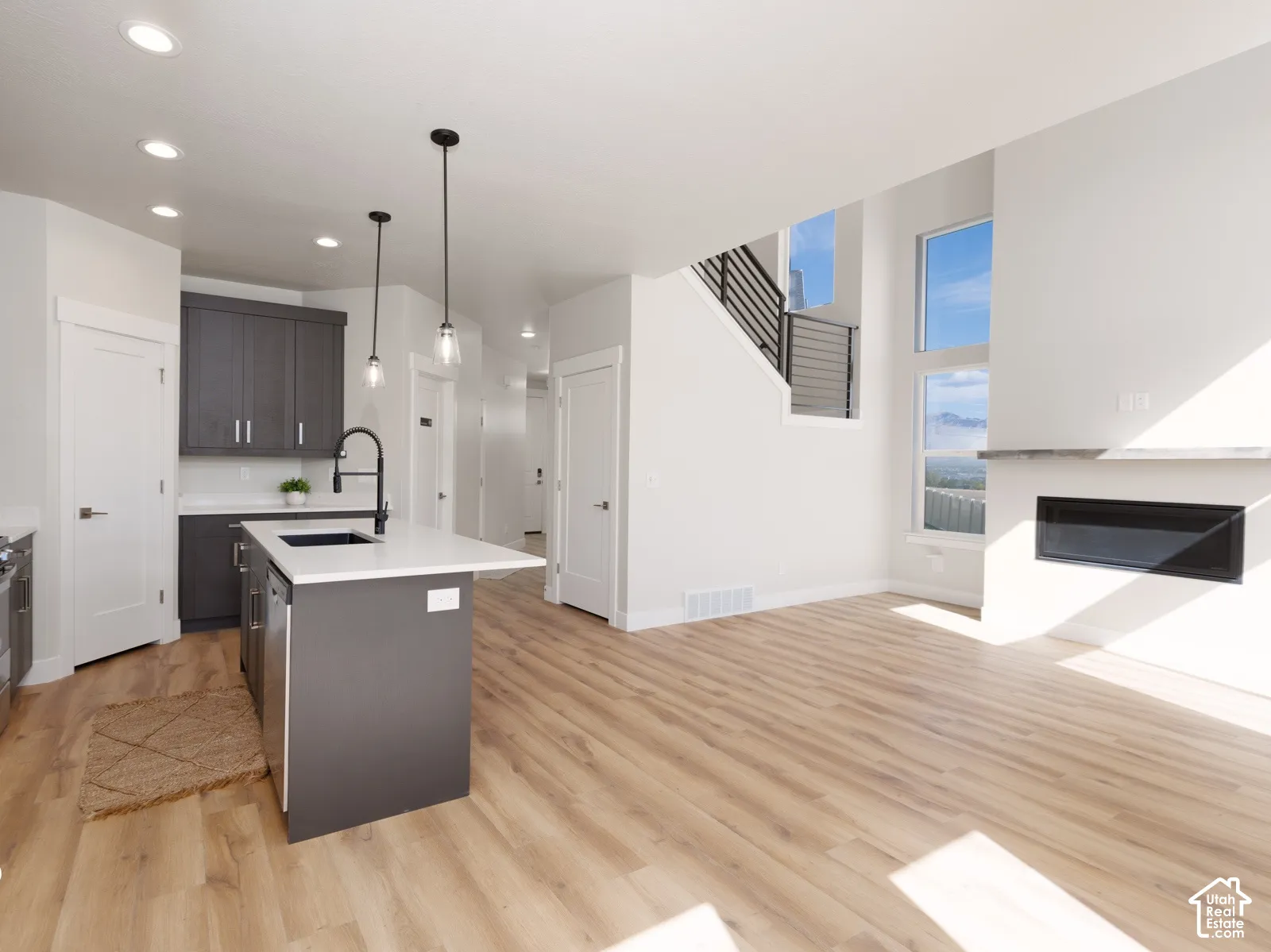 Bright living area featuring a built-in fireplace with a stone-finish mantel, wood-finish flooring, and a modern stair railing